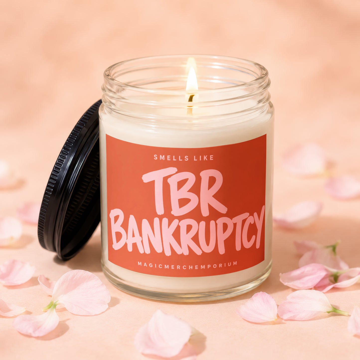 Candle with illuminated wick and orange label that says "Smells Like TBR Bankruptcy".