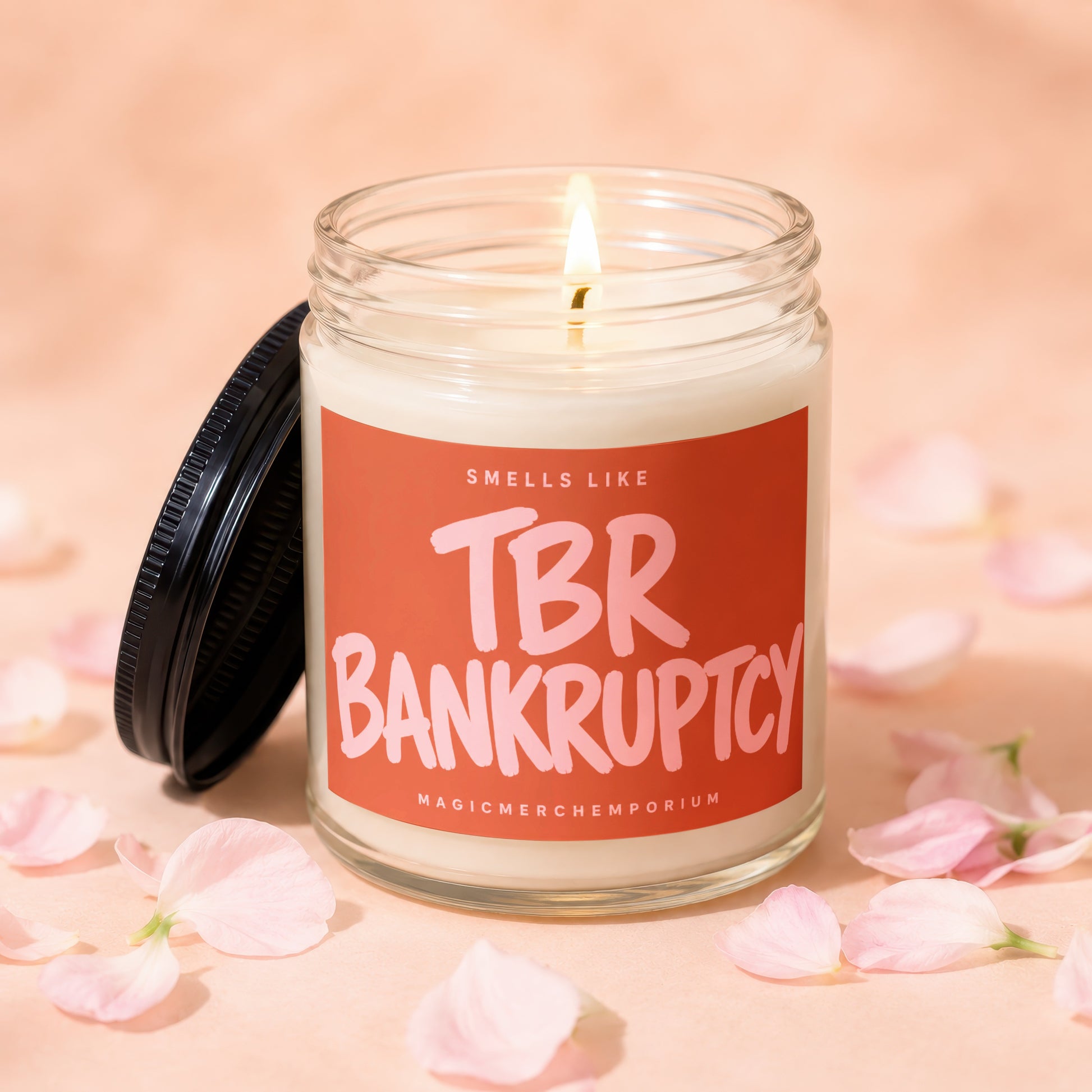 Candle with illuminated wick and orange label that says "Smells Like TBR Bankruptcy".