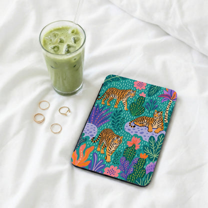 Tablet case with tigers and tropical plants on teal background, beside iced green drink and rings.