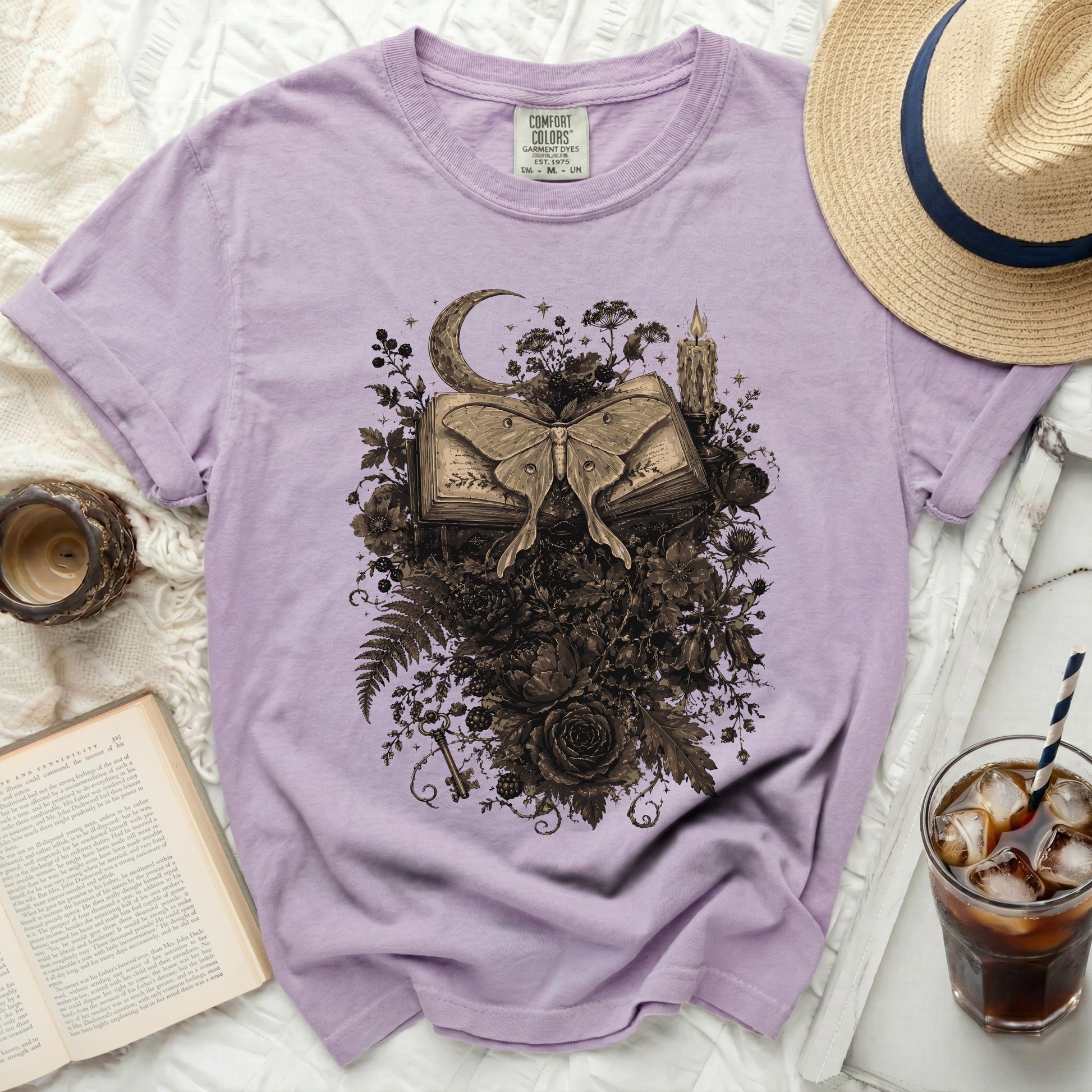 Lavender t-shirt featuring a dark moth, open book, moon, and floral design.