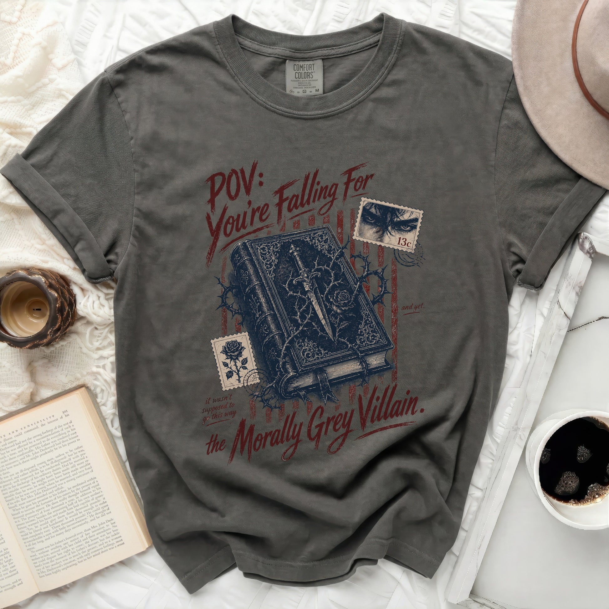 Dark grey t-shirt with a book, thorns, and text: "POV: You're Falling For the Morally Grey Villain."