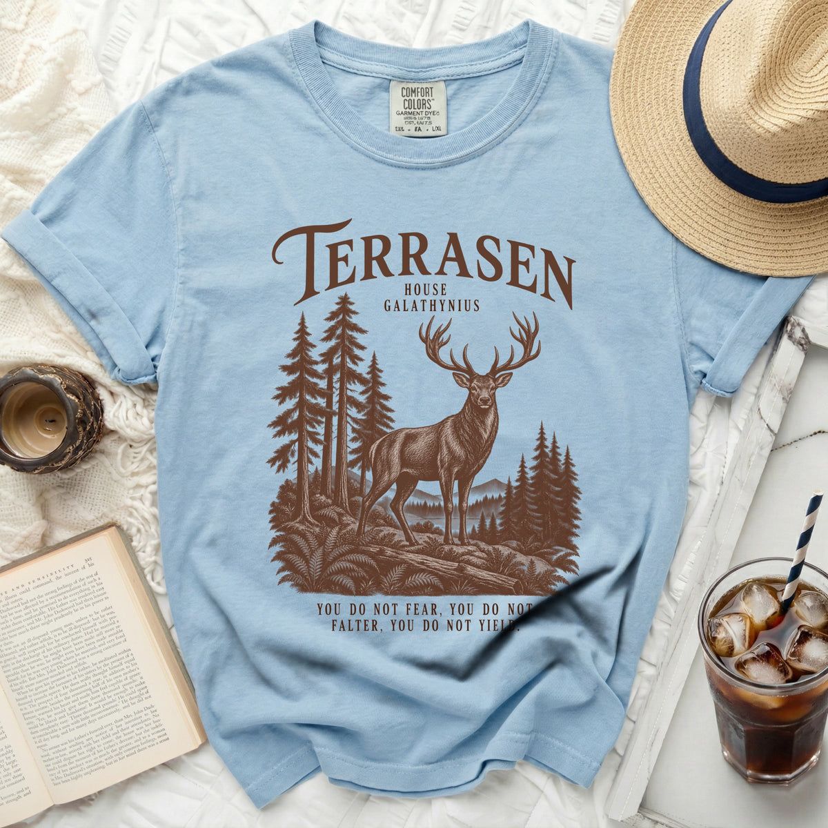 Light blue t-shirt with brown stag, trees, and quote "You do not fear, you do not falter, you do not yield."