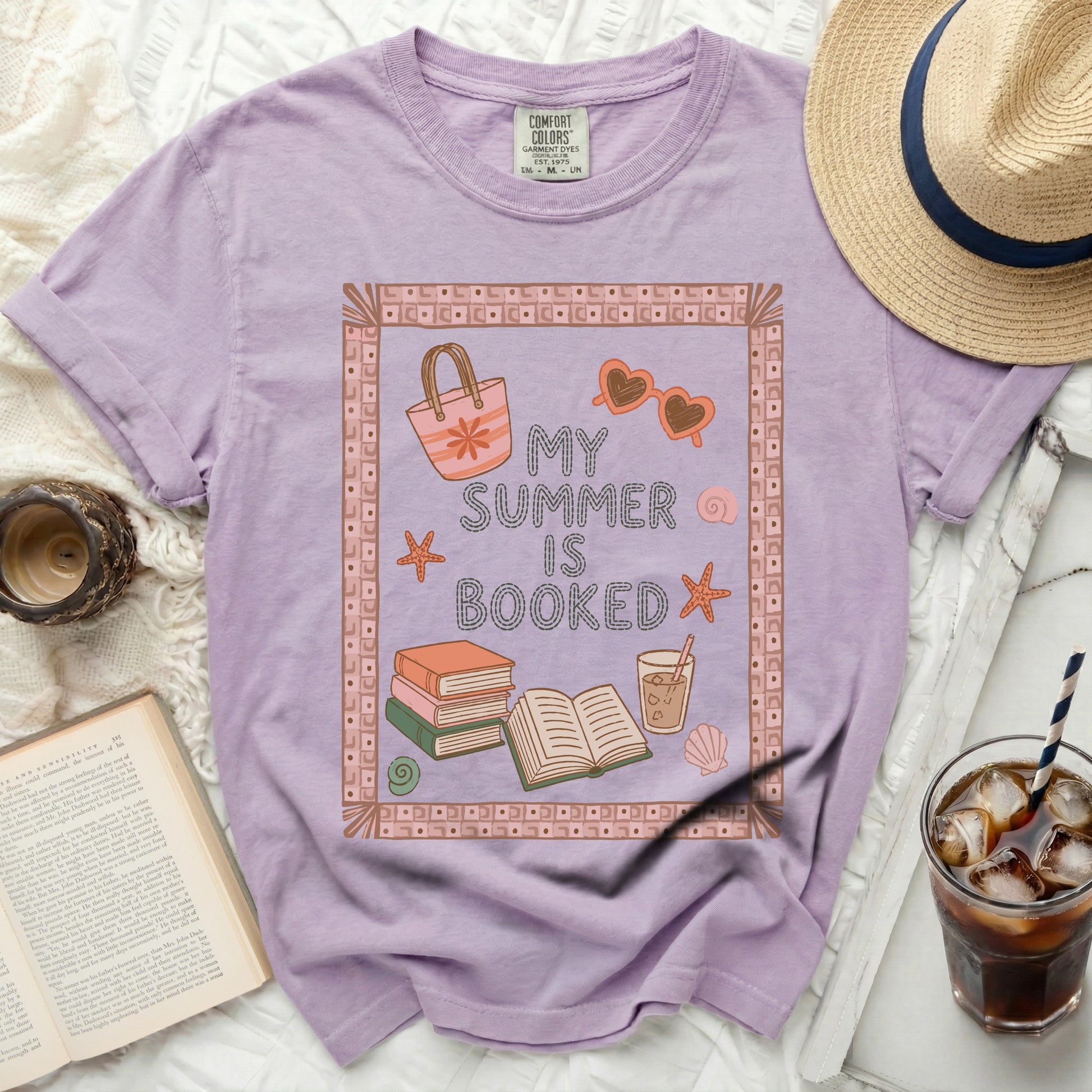Purple t-shirt with "My Summer Is Booked" text, books, and beach motifs.