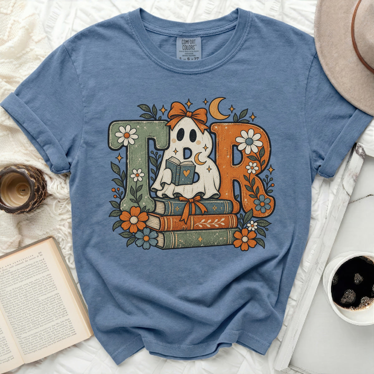 Ghost reading books with "TBR" text and floral accents on blue t-shirt.