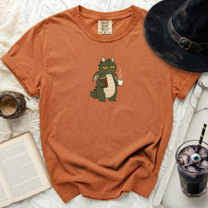 Orange Comfort Colors t-shirt with a green dragon holding a book and coffee.