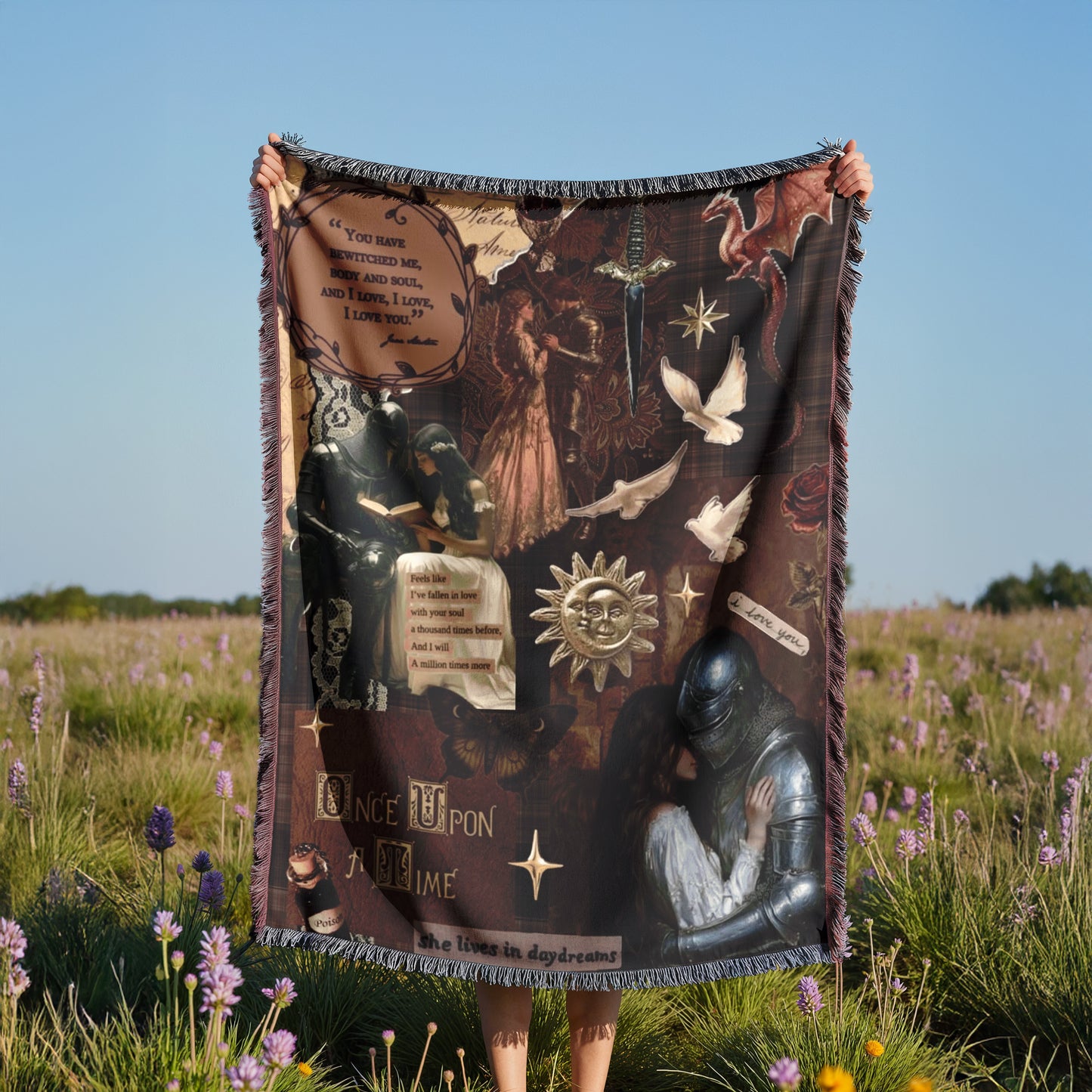 A person is holding up a large blanket with various images and text on it, standing in a field with purple flowers.