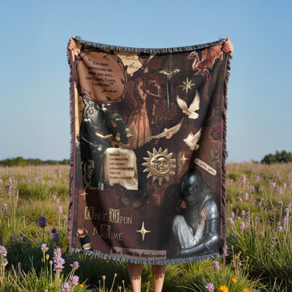 A person is holding up a large blanket with various images and text on it, standing in a field with purple flowers.