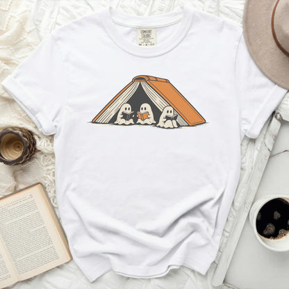 White t-shirt with graphic of three ghosts reading inside an open orange book.