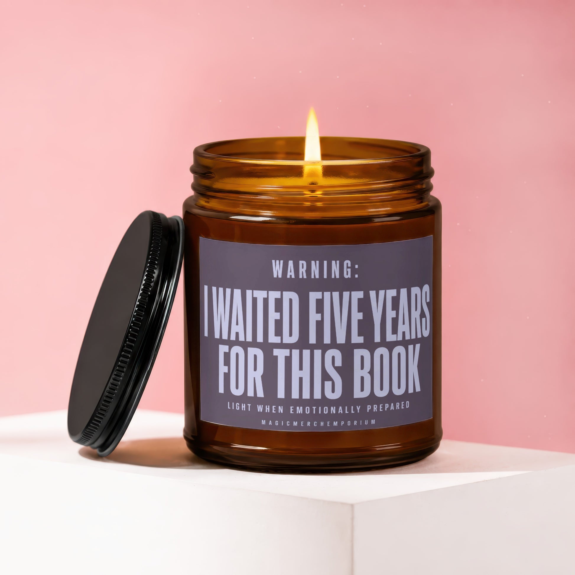 Amber jar candle with lit wick, reading "WARNING: I WAITED FIVE YEARS FOR THIS BOOK".