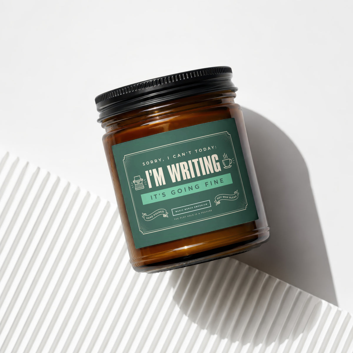 Amber jar candle with green label reading "Sorry, I can't today: I'm writing. It's going fine."