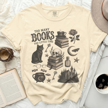 Cream t-shirt with graphic of cat, books, skull, cauldron, castle, and text "Too Many Books Too Little Time."