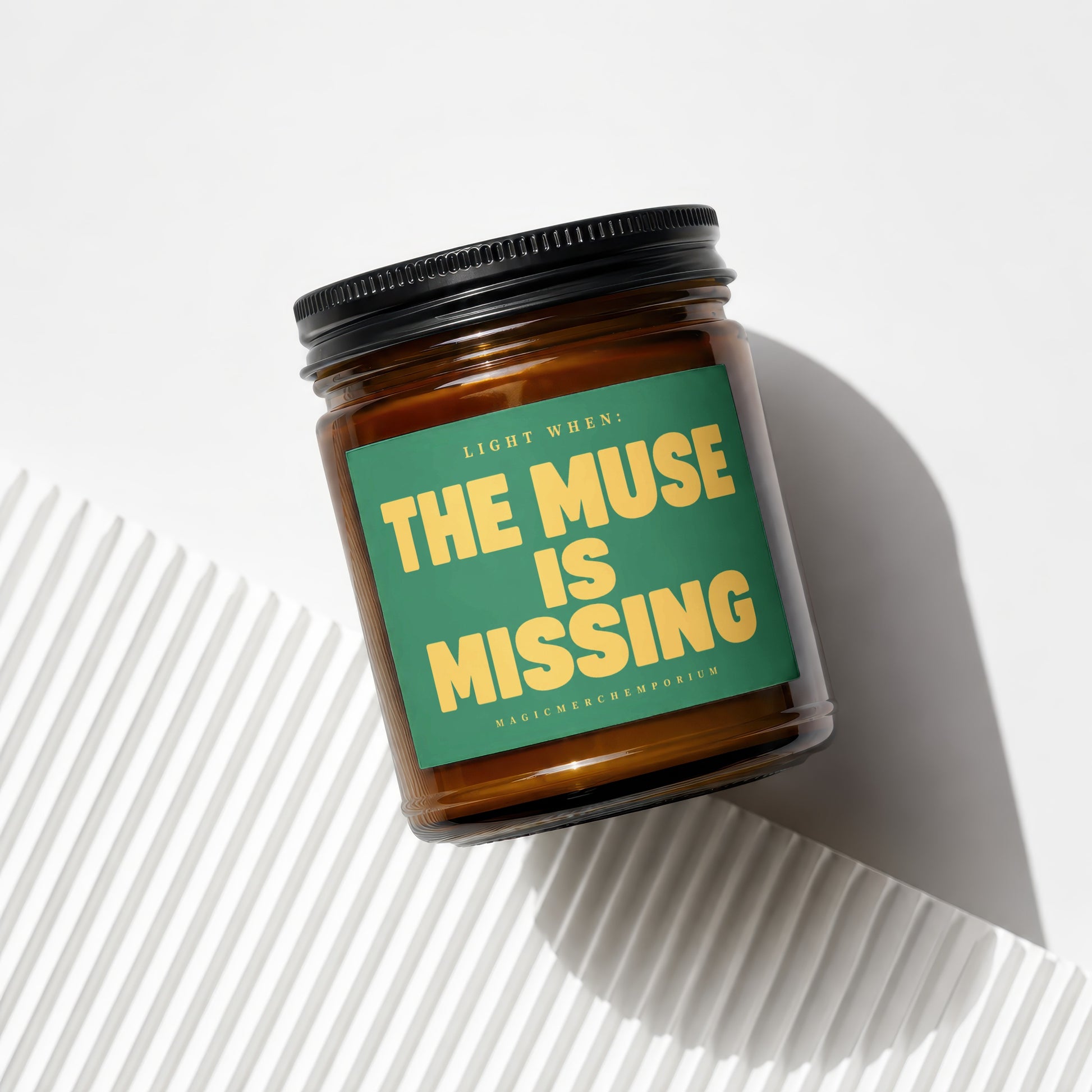 Amber jar candle with green label reading "THE MUSE IS MISSING"