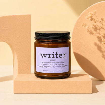 Brown glass candle with "writer noun" definition label and "MAGICMERCHEMPORIUM" text.