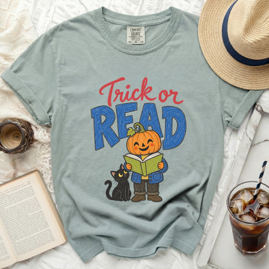 Pumpkin reading to black cat with text "Trick or READ" on shirt.
