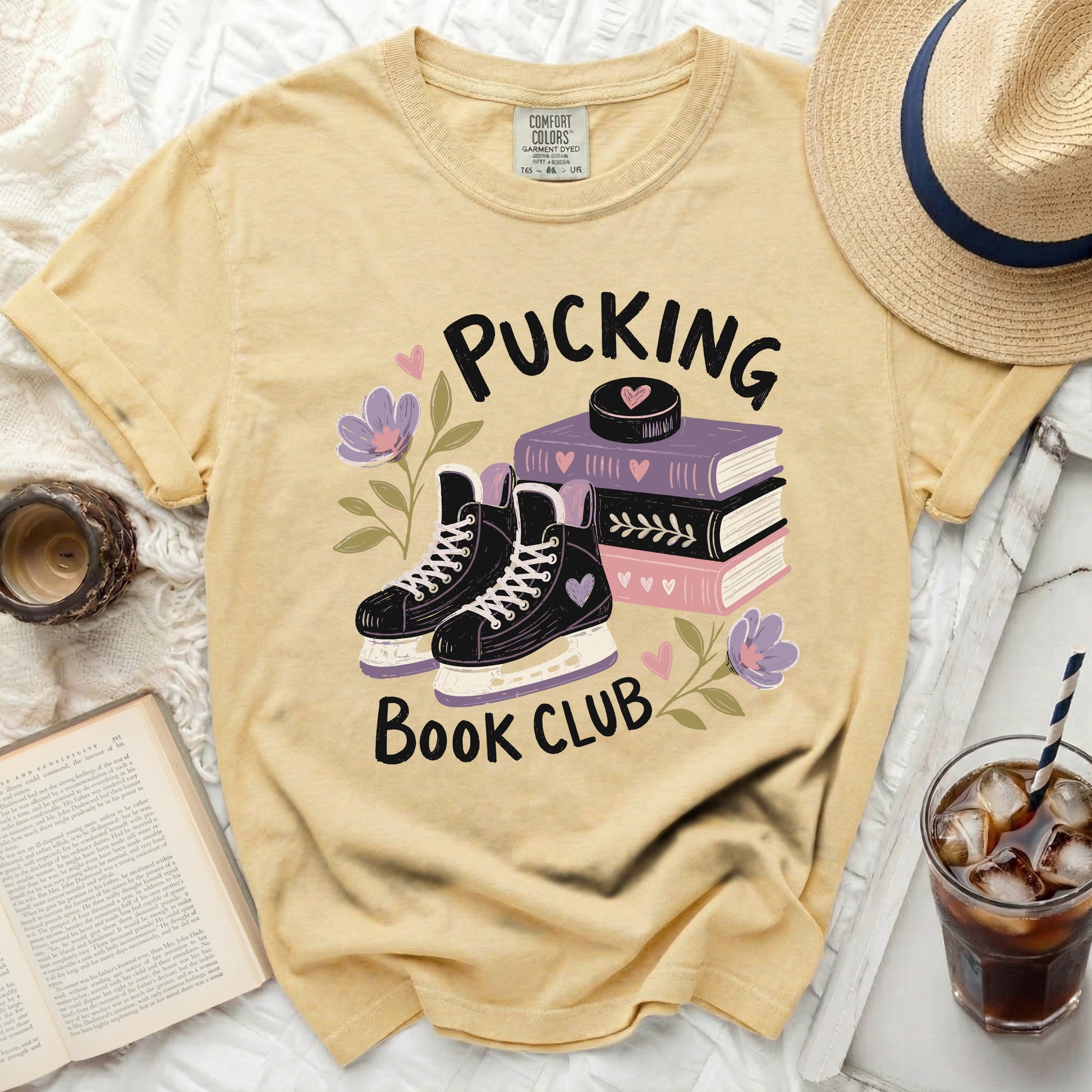 Yellow t-shirt with "Pucking Book Club" text, hockey skates, books, and flowers.