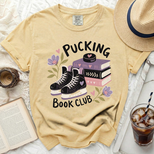 Yellow t-shirt with "Pucking Book Club" text, hockey skates, books, and flowers.