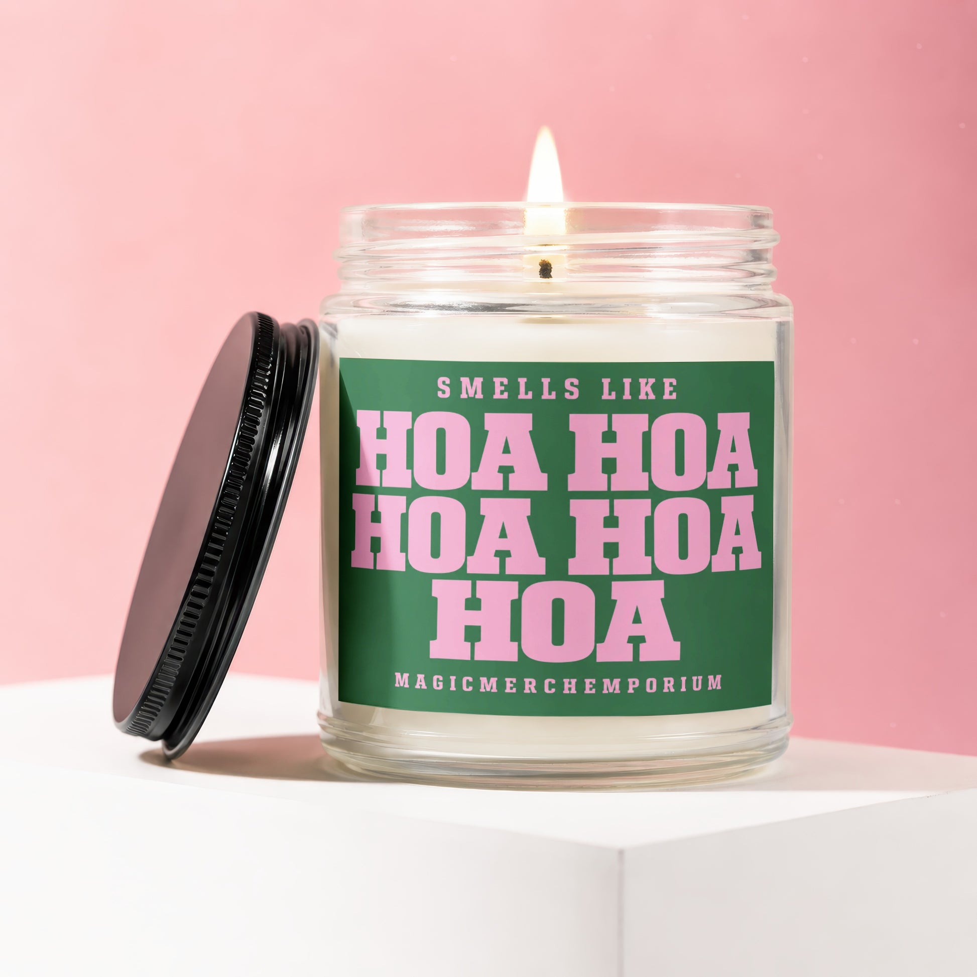 Candle with green label saying "Smells Like Hoa Hoa Hoa Hoa" on pink background.