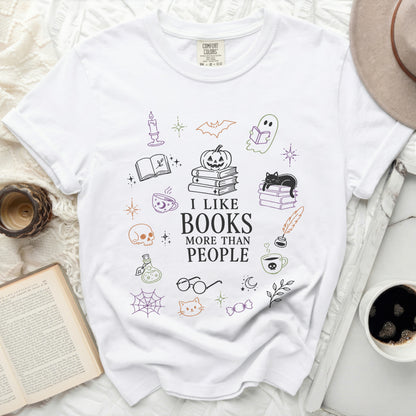 White t-shirt with "I LIKE BOOKS MORE THAN PEOPLE" and Halloween-themed illustrations.
