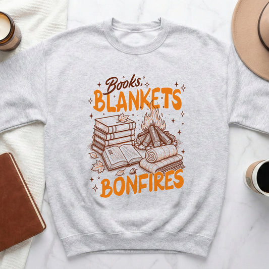 Light grey sweatshirt with orange text "Books, Blankets, Bonfires," books, logs, and a fire.