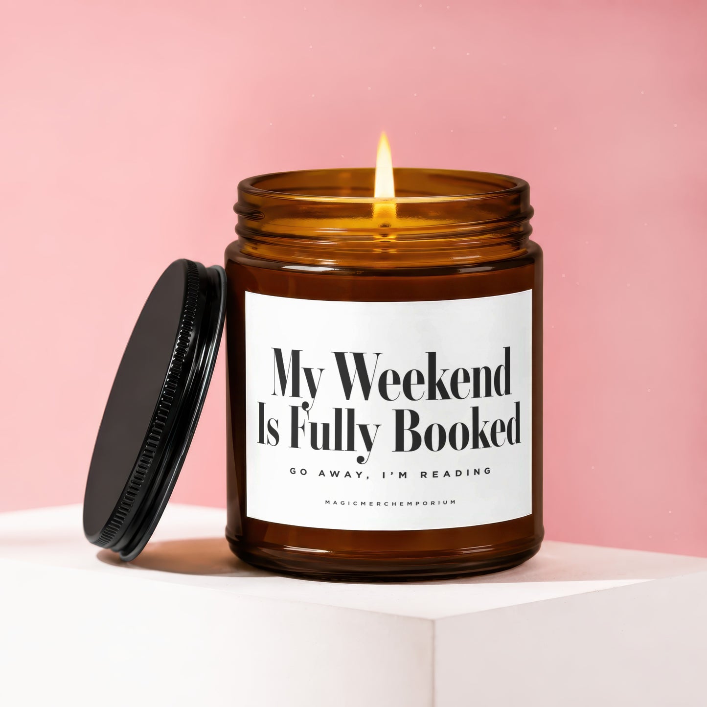 Amber glass candle with lit flame, lid off. Label reads "My Weekend Is Fully Booked".