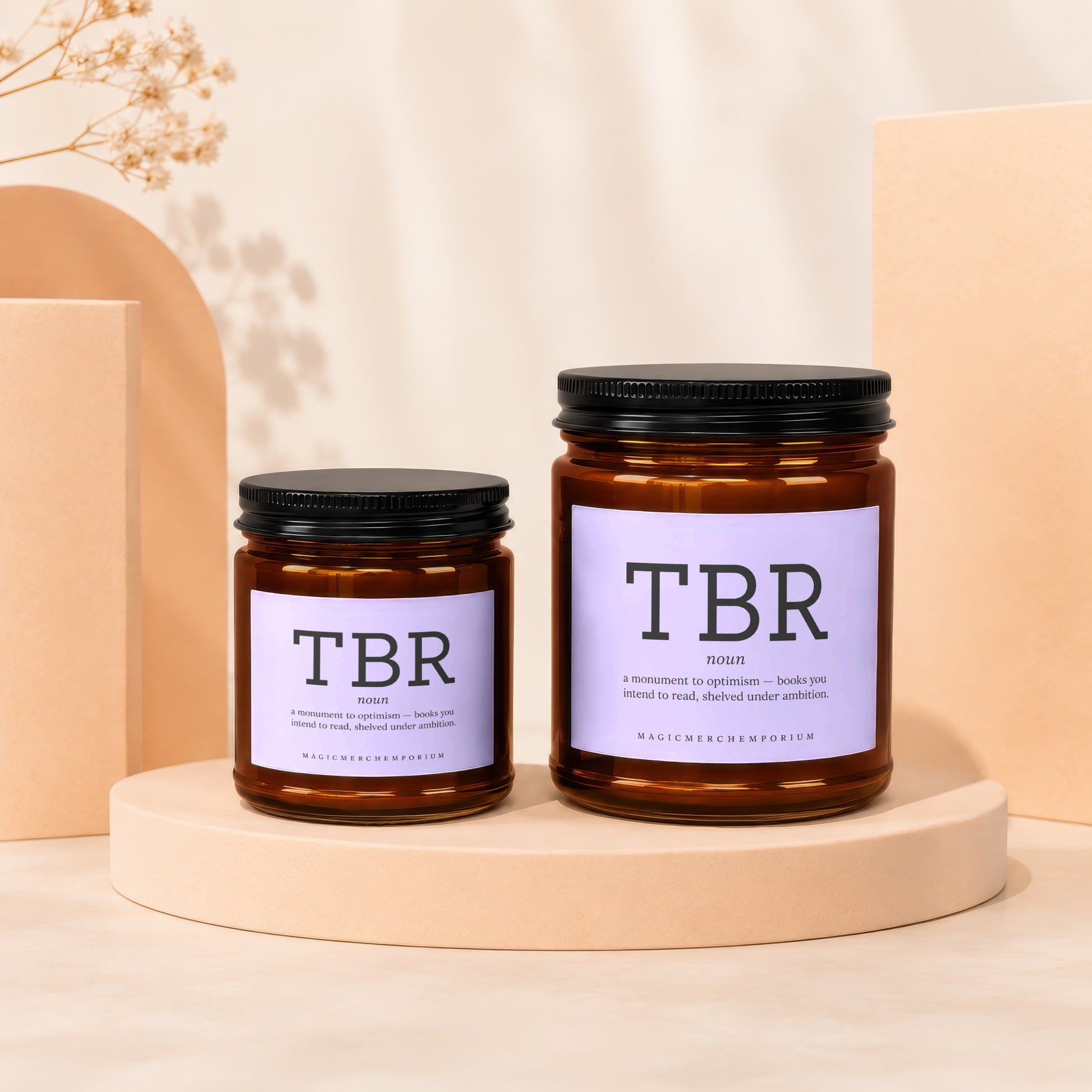 Two amber glass candles labeled "TBR" sit on a display with text about books.