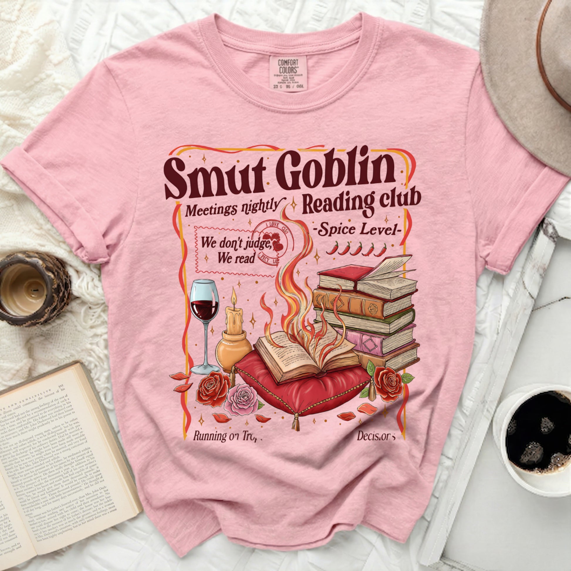 Pink t-shirt with "Smut Goblin Reading Club" graphic and book-themed illustration.