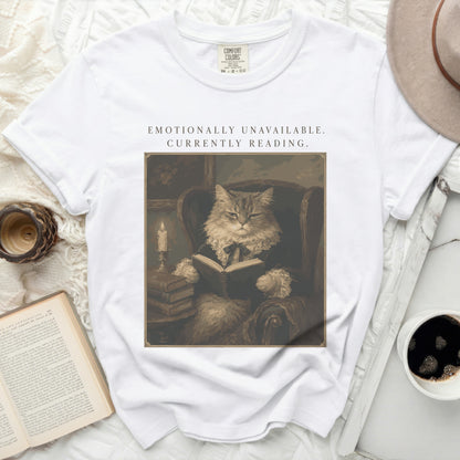 White t-shirt with graphic of cat reading book, text "EMOTIONALLY UNAVAILABLE. CURRENTLY READING."