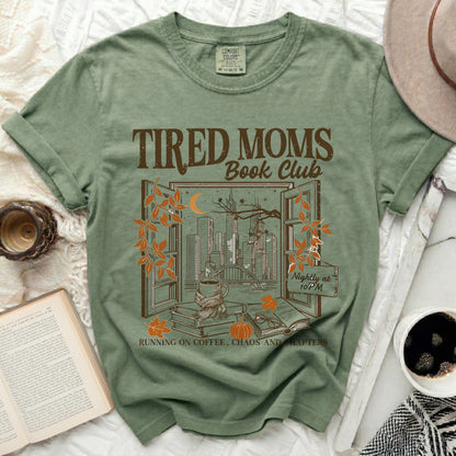 Green t-shirt with "Tired Moms Book Club" graphic of city through window.