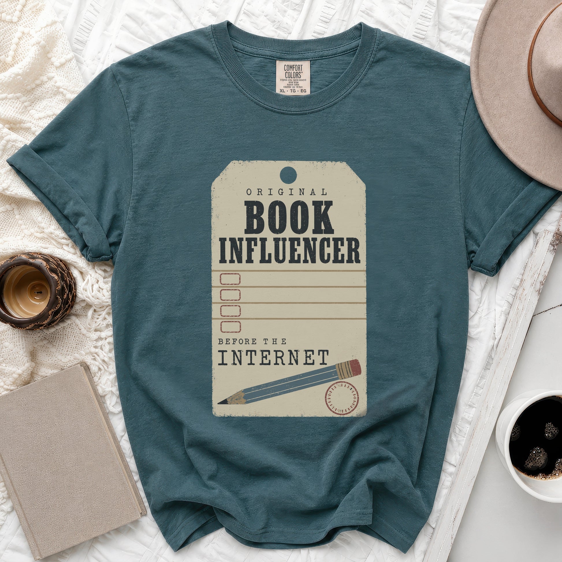 Teal t-shirt with "Original Book Influencer Before The Internet" graphic and pencil.