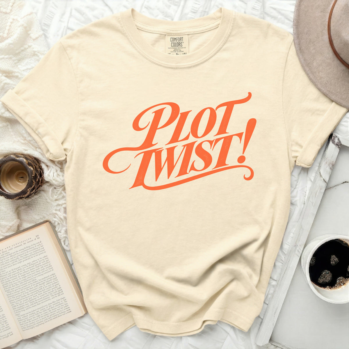Cream t-shirt with "PLOT TWIST!" graphic in orange script font.