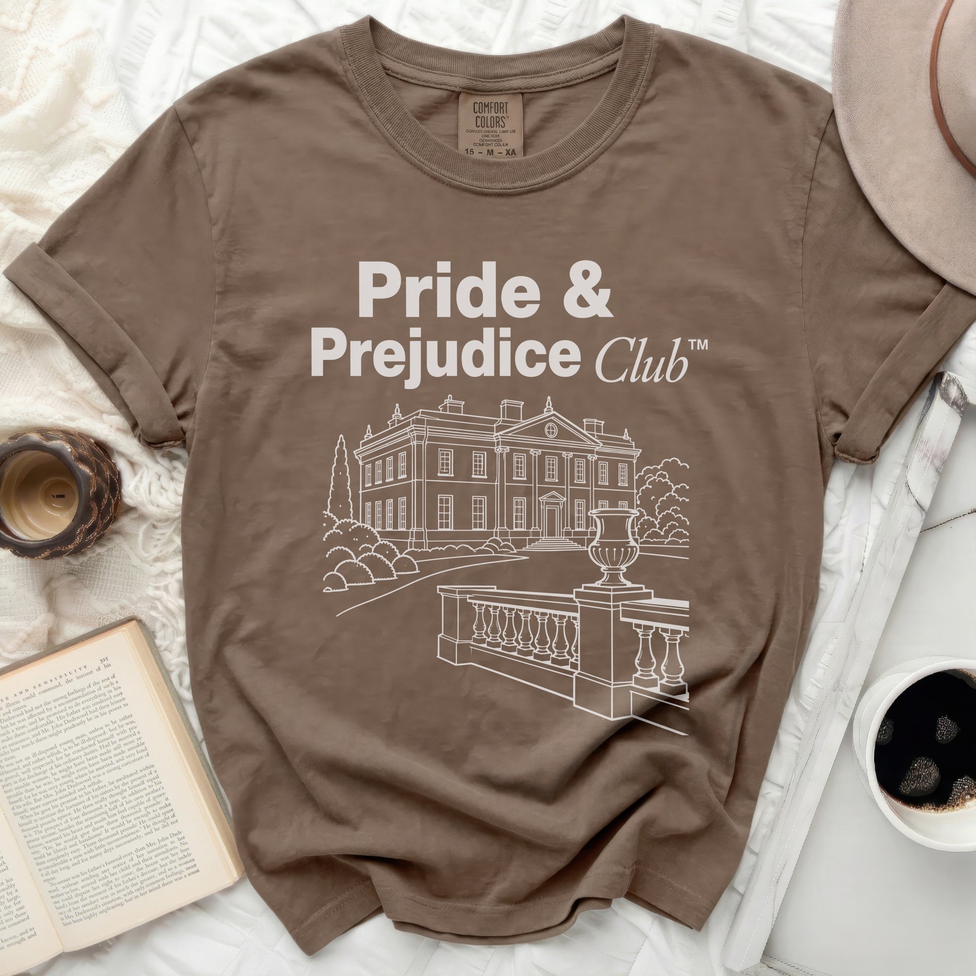 Brown t-shirt with "Pride & Prejudice Club" text and building graphic.