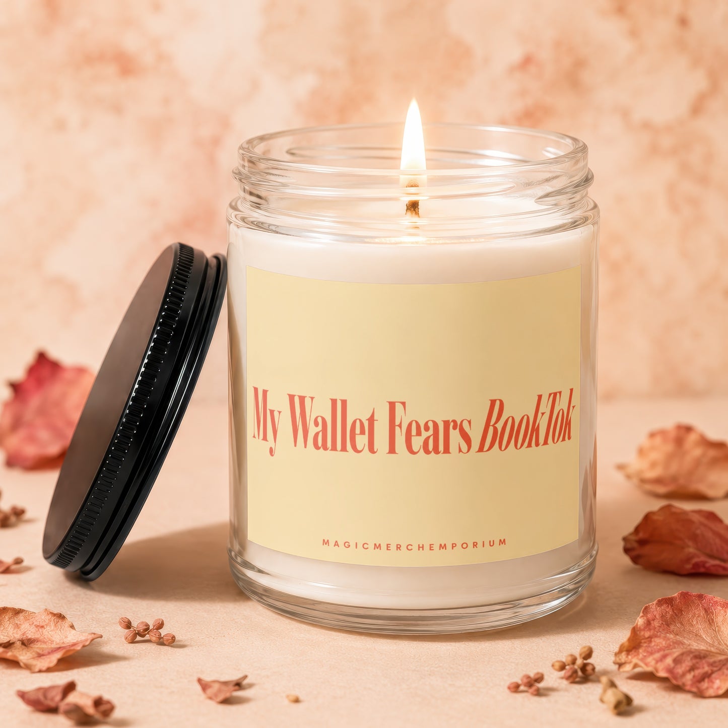 Lit candle with "My Wallet Fears BookTok" on a yellow label, lid off.