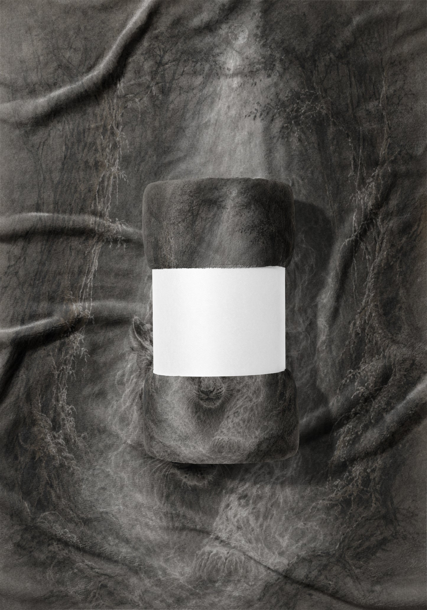Rolled fleece blanket with blank white band on a textured gray fabric background.