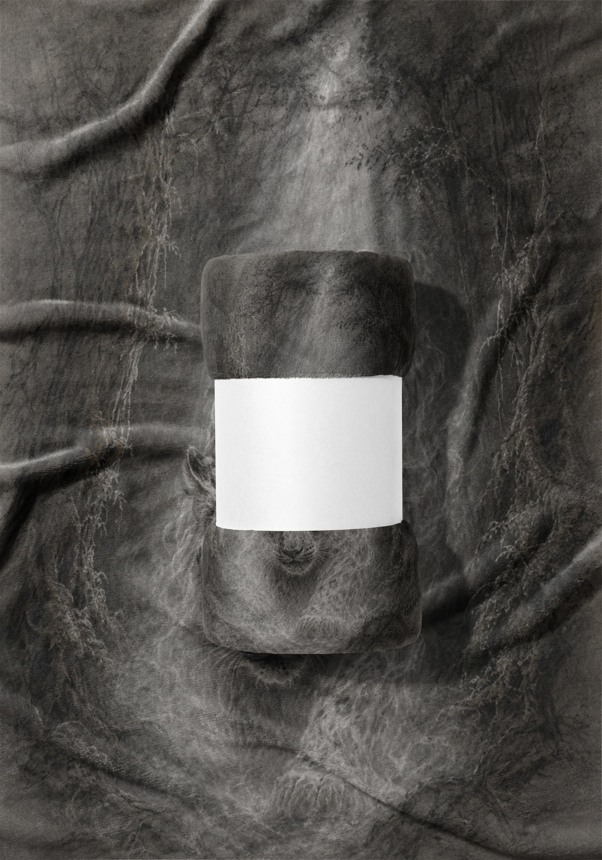 Rolled fleece blanket with blank white band on a textured gray fabric background.