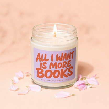 Jar candle with lit wick and label reading "ALL I WANT IS MORE BOOKS MAGICMERCH".