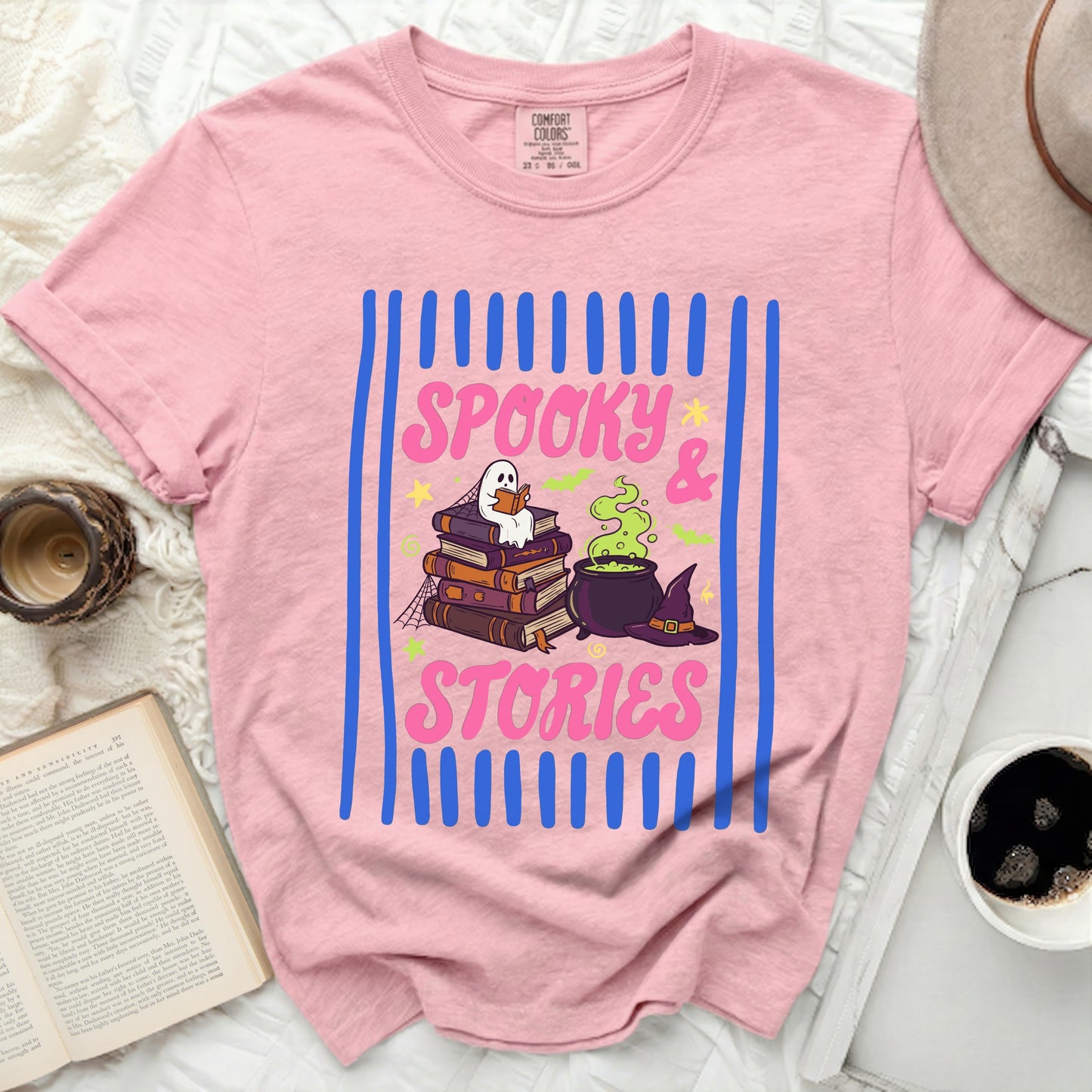 Pink t-shirt with "Spooky & Stories" graphic featuring books, ghost, cauldron, and witch hat.