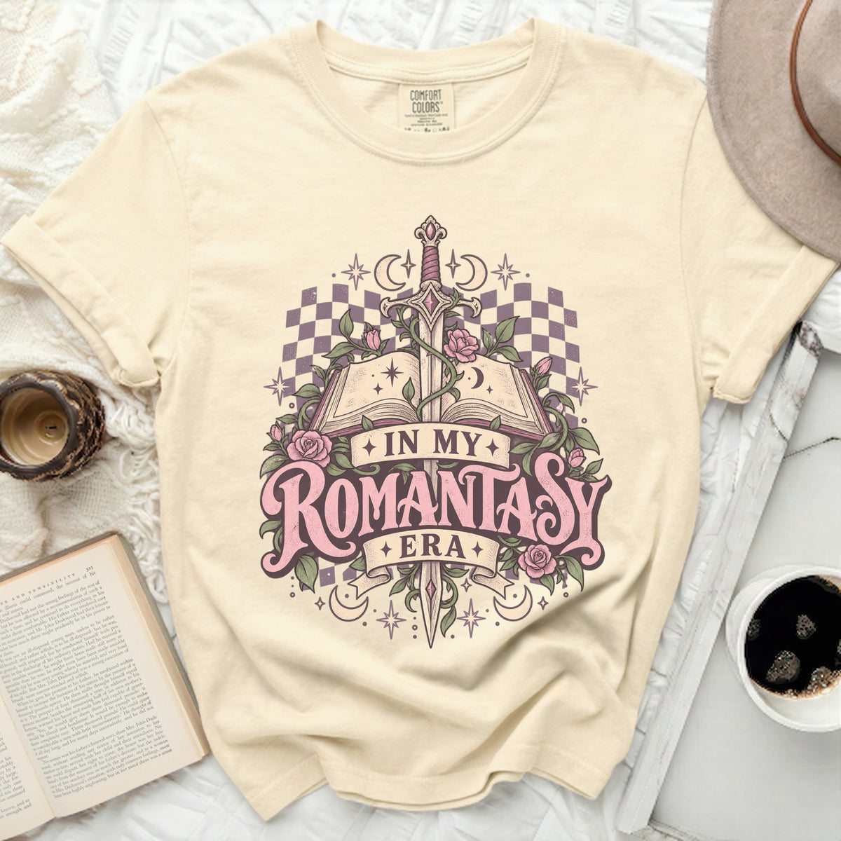 Cream t-shirt with "In My Romantasy Era" graphic featuring an open book, sword, roses, and moons.