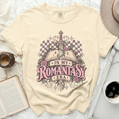 Cream t-shirt with "In My Romantasy Era" graphic featuring an open book, sword, roses, and moons.