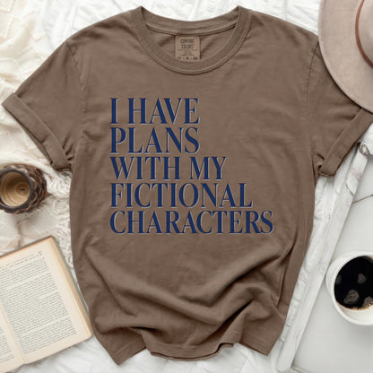 Brown t-shirt with "I HAVE PLANS WITH MY FICTIONAL CHARACTERS" in blue text.