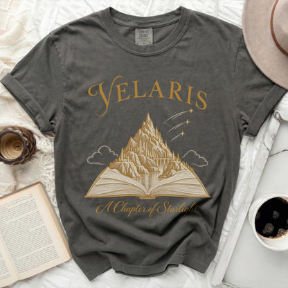 Grey t-shirt with gold graphic of "Velaris" over a mountain castle and open book.