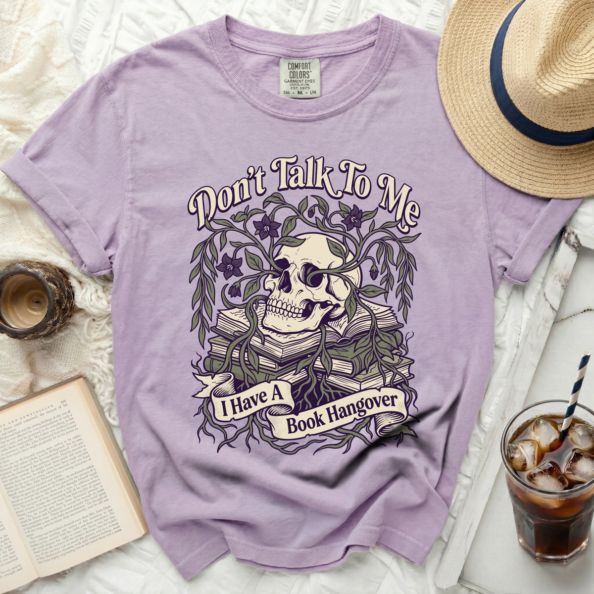 Purple t-shirt with a skull, books, and vines graphic saying "Don't Talk To Me I Have A Book Hangover".