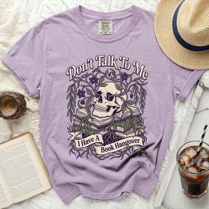 Purple t-shirt with a skull, books, and vines graphic saying "Don't Talk To Me I Have A Book Hangover".
