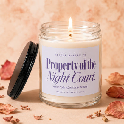 Lit candle in glass jar with "Property of the Night Court" label and dark lid.