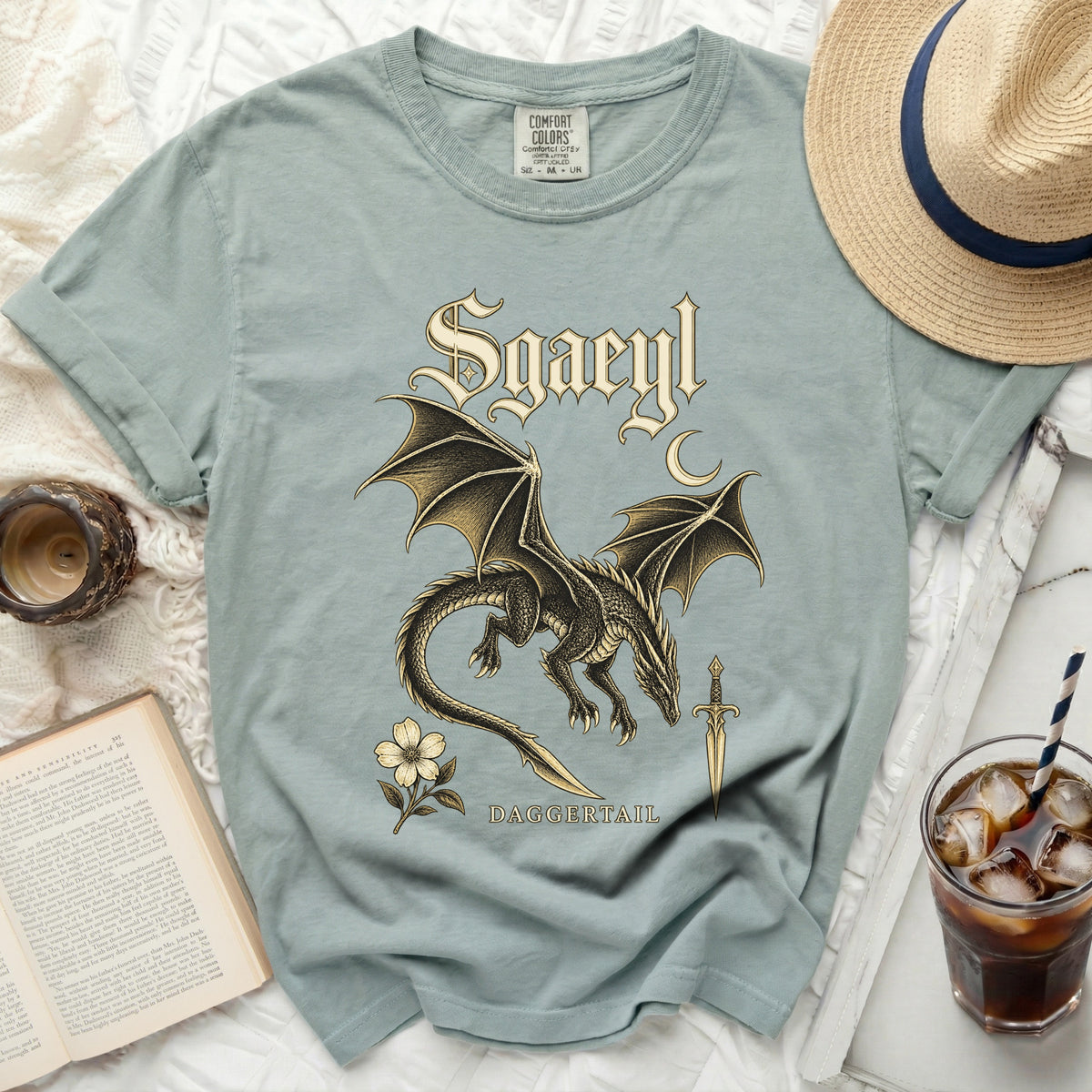 Sgaeyl text graphic on a t-shirt with dragon, dagger, and flower designs.