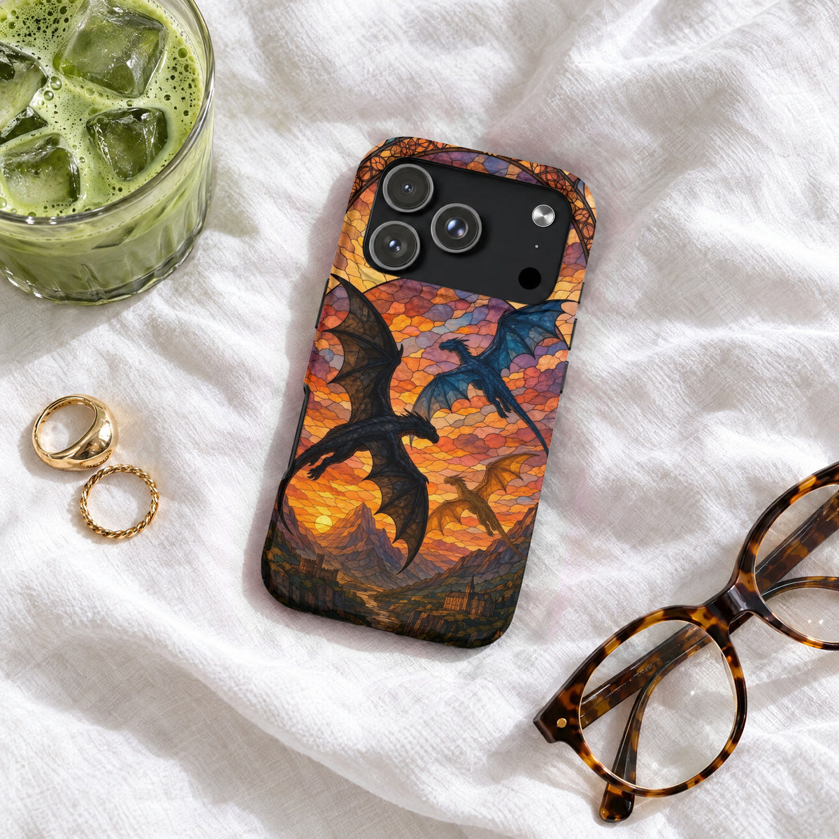 A phone case featuring a stained glass design of three dragons flying over a mountainous landscape at sunset.
