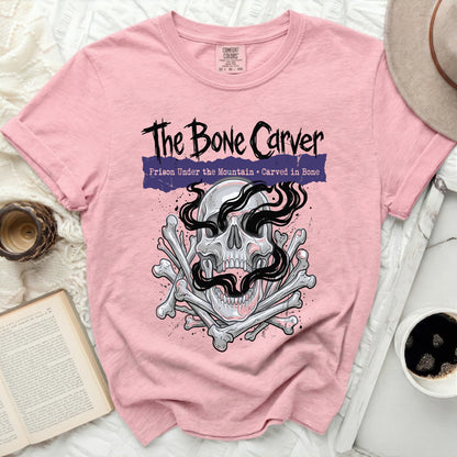 Pink t-shirt with "The Bone Carver" text and skull graphic.