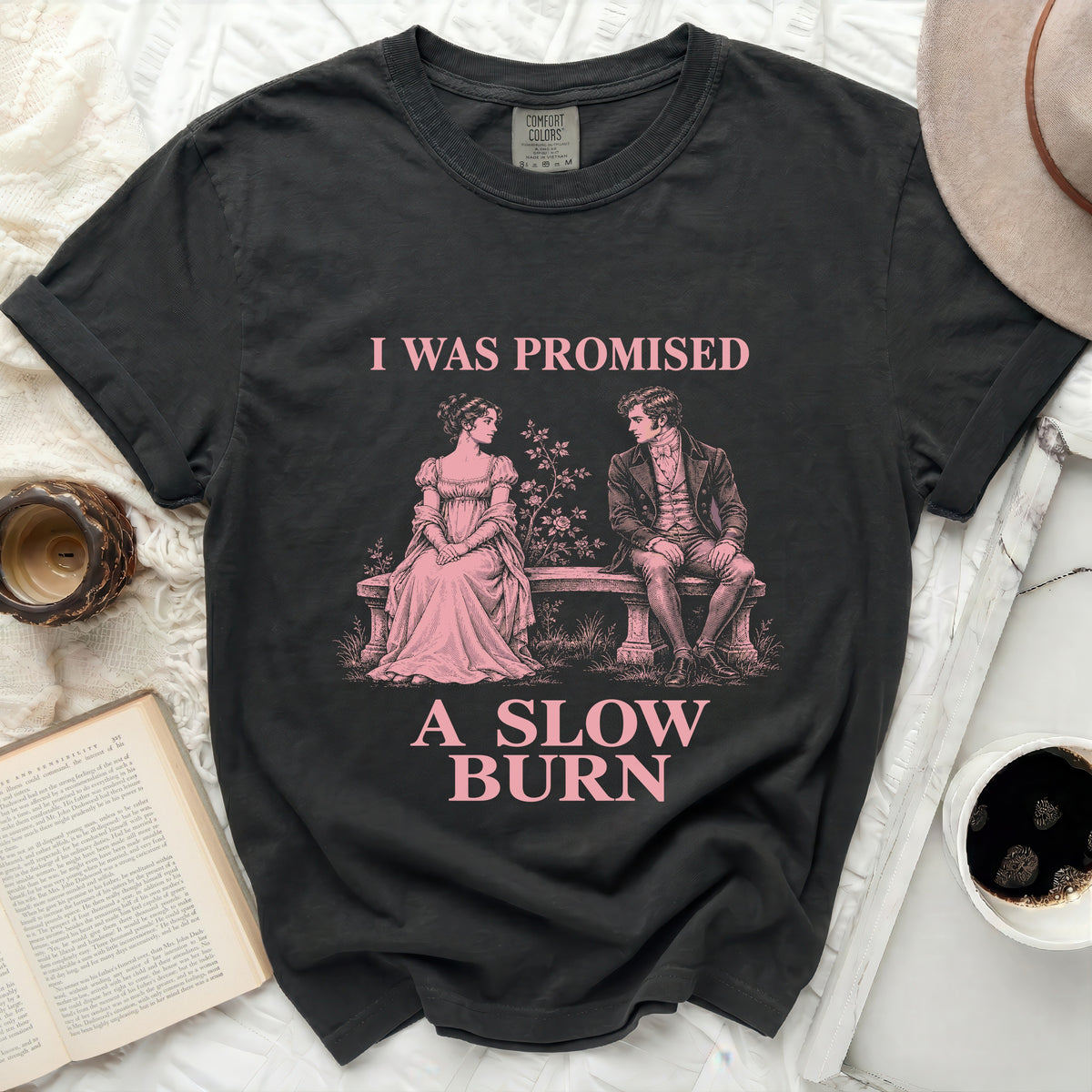 Dark t-shirt with pink graphic of couple and text "I WAS PROMISED A SLOW BURN".