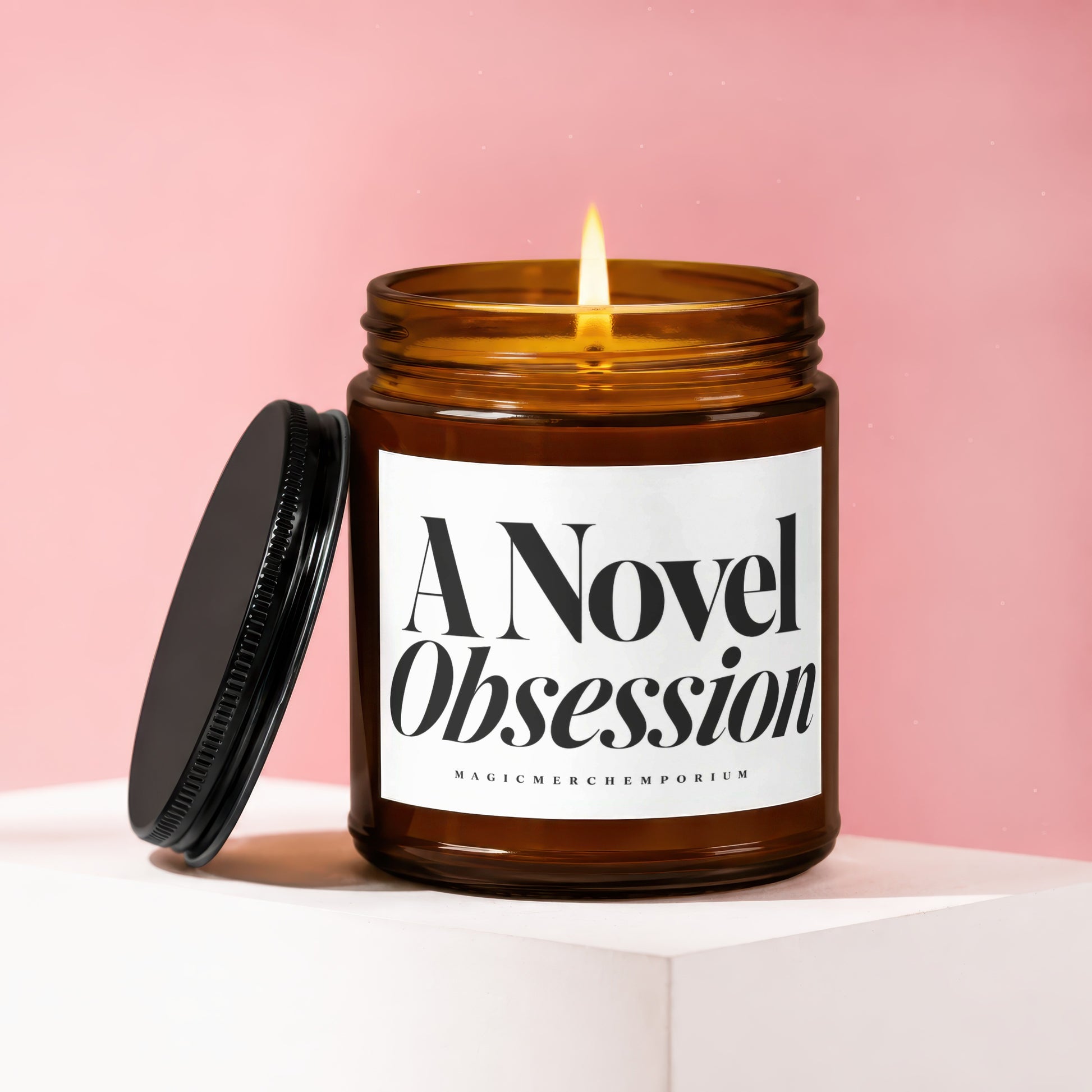 Amber jar candle with lit flame reads "A Novel Obsession" and "MAGICMERCHEmporium."