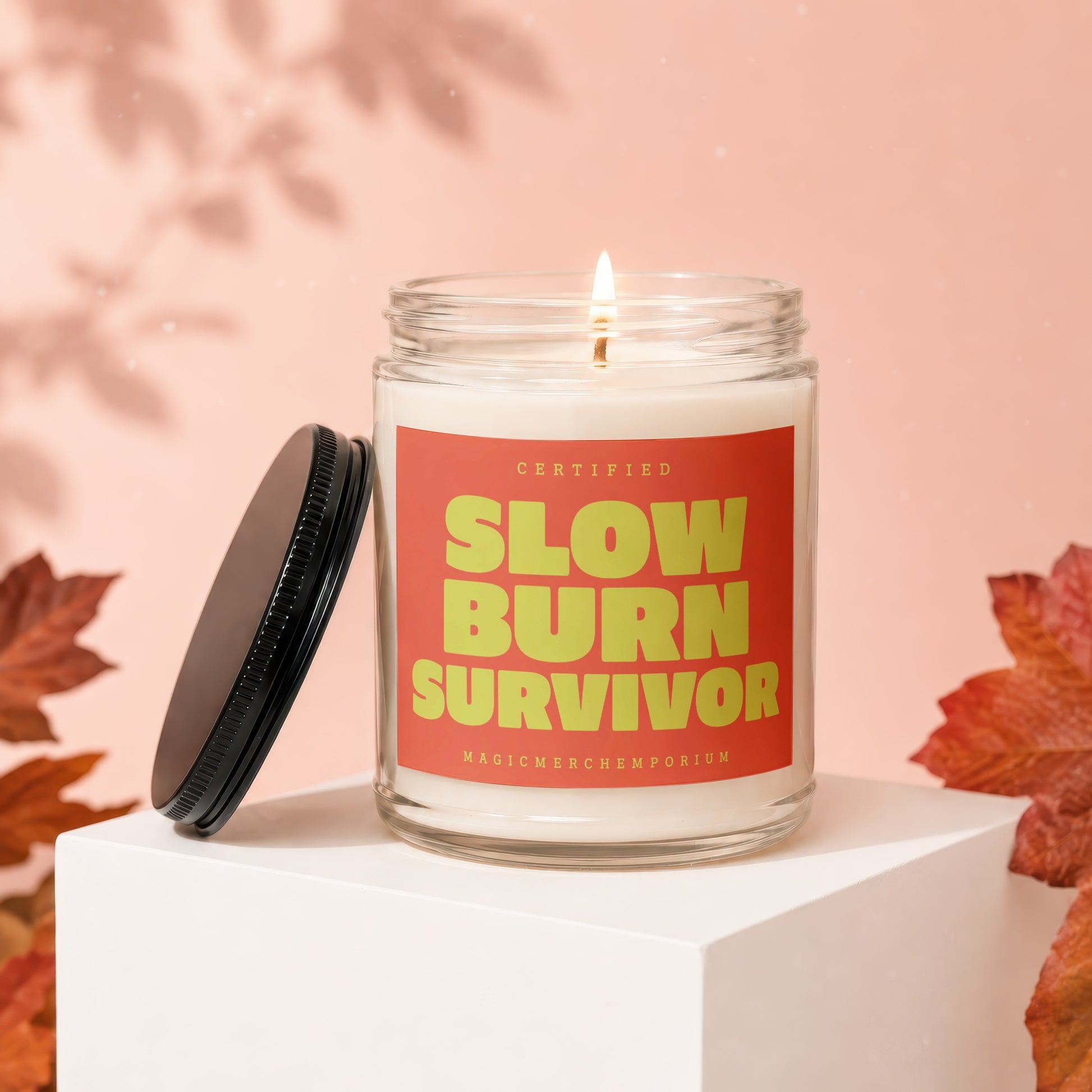Burning candle in a glass jar with a red label that says "CERTIFIED SLOW BURN SURVIVOR".