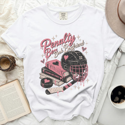 White t-shirt with "Penalty Book Boyfriend" hockey graphic and books.